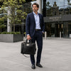 Man in a suit with a Luxury Leather Laptop Bag, standing outside a modern building.