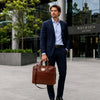 Man wearing a suit carrying a Luxury Leather Laptop Bag in a modern urban setting.
