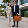 Professional couple holding a Leather Laptop Briefcase Bag in a modern outdoor setting.