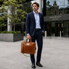 Man in a suit holding a Luxury Leather Laptop Bag in an urban setting.