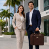 A professional couple posing outdoors, the man holding a Leather Laptop Briefcase Bag in a business setting.