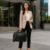 Woman in business attire holding a Leather Business Laptop Bag outside a modern office building.