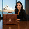 Elegantly designed Leather Laptop Briefcase placed on a table, with a woman in a suit in a modern office setting.
