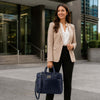 Woman in a business suit holding a Leather Business Laptop Bag, standing outside an office building.