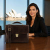 Leather Laptop Briefcase on a table with a woman in a professional setting, showcasing style and functionality.
