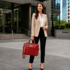 Professional woman in a blazer holding a red Leather Business Laptop Bag outside a modern building.