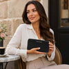 Woman holding Ladies Leather Zip Around Wallet at a cafe, showcasing style and elegance.