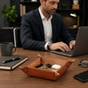 Large Leather Desk Tidy Tray with keys and airpods on a desk next to a man working on a laptop.