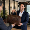 Man receiving a Leather Travel Gift Set, featuring a duffle bag and accessories, in a professional setting.