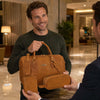 Man holding Leather Travel Gift Set including duffle bag, toiletry bag, and passport cover in hotel lobby.
