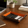 Leather Valet Tray on a wooden desk, holding phones, cards, and a pen, perfect for organizing everyday essentials.