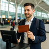 Man in a suit holding a Leather Passport Wallet at an airport check-in desk.