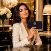 Luxury Zip Around Leather Wallet held by a woman in a classy setting with flowers and ambient lighting.