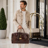 Man carrying a Luxury Leather Travel Bag at a stylish hotel entrance.