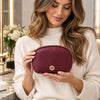 Woman holding the Luxury Soft Leather Toiletry Case in bordeaux pebbled leather with a gold-tone zipper and logo.
