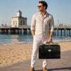 Man in beach setting holding Gladstone Leather Bag, showcasing style and sophistication.