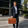 Mens Leather Messenger Bag held by a man in a suit outdoors, showcasing style and functionality.