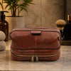 Mens Toiletry Bag Leather on a marble countertop with toiletries in the background, ideal for men's grooming essentials.