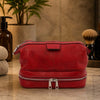Mens Toiletry Bag Leather in red placed on a countertop with toiletries.