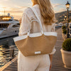Woman carrying a Leather Shopping Bag with a stylish design by the waterfront at sunset.