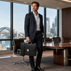 Professional Leather Briefcase held by a businessman in a sleek suit with a city skyline in the background.