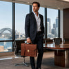 Professional Leather Briefcase carried by a man in a suit with a city skyline in the background.
