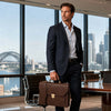 Professional Leather Briefcase worn by a man in a suit inside a modern office with a city view.