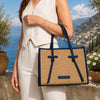 Raffia Shoulder Bag displayed outdoors against a scenic backdrop, showcasing its natural texture and stylish design.