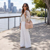 Woman wearing a stylish outfit holding a Leather Bucket Bag near a waterfront view.