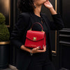 Small Leather Shoulder Bag held by a woman in a black outfit, showcasing an elegant red design.