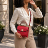Stylish woman holding a Small Leather Shoulder Bag in lipstick red, showcasing its elegant design and versatility.