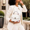 Small Leather Shoulder Bag worn by a woman in a white suit, showcasing its elegance and design.