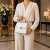 Small Leather Shoulder Bag being held by a woman in a stylish outfit in an elegant setting.