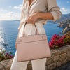 Small Tote Bag held by a person against a scenic coastal backdrop with vibrant flowers.