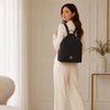 Woman wearing a Soft Leather Backpack in black with elegant design and gold-tone hardware.