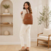 Woman wearing a cognac Soft Leather Backpack in a stylish modern interior.