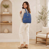 Woman wearing a blue Soft Leather Backpack, showcasing its stylish design and practicality in a cozy indoor setting.