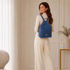 Woman wearing a denim Soft Leather Backpack, showcasing its soft structure and gold-tone hardware, ideal for daily use.