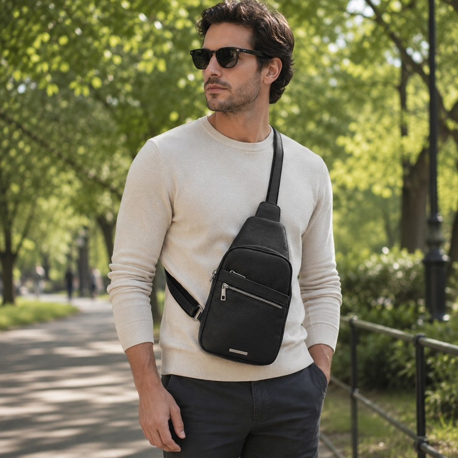 Man wearing a black soft leather crossbody bag in a park