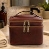 Travel Toiletry Bag in rich leather on a marble countertop, featuring dual zipped closures and sturdy handle.