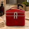 Travel Toiletry Bag in red leather with dual zippers and handle on a marble countertop