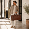 Man in casual outfit carrying Leather Duffle Bag Large in an elegant setting.
