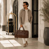 Man in stylish outfit carrying Leather Duffle Bag Large in luxury setting.