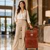 Woman in a stylish outfit standing with 4 Wheeled Luggage in a luxurious hotel lobby.