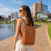 Leather Backpack Ladies worn by a woman on a waterfront path with a city skyline in the background.