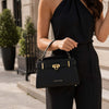 Womens Leather Tote Bag held by a woman in black outfit, showcasing its elegant design and gold accents.