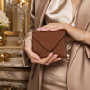 Womens Leather Wallet held by a woman, showcasing its elegant cognac pebbled leather design and stylish closure.