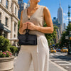 Womens Leather Clutch held by a woman in a city street with skyscrapers in the background.