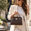 Beautiful woman holding the Womens Leather Tote Bag in Coffee featuring a sleek design and gold hardware.