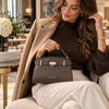 Beautiful woman holding the Womens Leather Tote Bag in Dark Taupe featuring a sleek design and gold hardware.